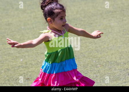 Little girl dances on the grass with her tongue sticking out Stock Photo