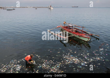 Manila, Philippines. 3rd July, 2014. A volunteer picks up garbage washed along the shore of Manila Bay in Roxas Boulevard during the International Plastic Bag-Free clean-up drive. Volunteers lead by Earth Island Institute of the Philippines and Miss Earth Foundation held a clean-up day in commemoration of the International Plastic Bag- Free day in Manila. Credit:  J Gerard Seguia/Pacific Press/Alamy Live News Stock Photo