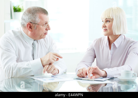 Two mature business partners discussing papers at meeting Stock Photo