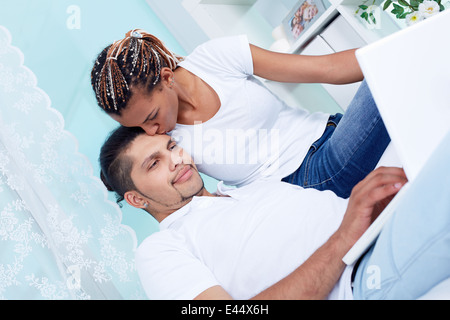 Image of young girl kissing her boyfriend using laptop
