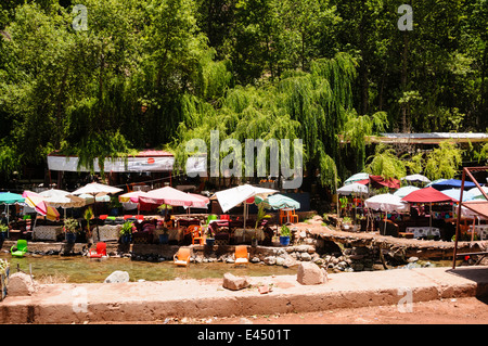 Plastic patio tables, chairs with parasols at restaurants on the banks of the Ourika River, Ourika Valley, Atlas Mountains, Morocco