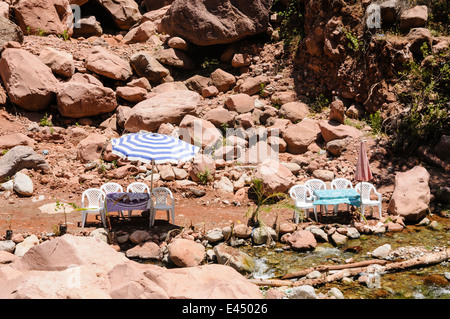Plastic patio tables, chairs with parasols at restaurants on the banks of the Ourika River, Ourika Valley, Atlas Mountains, Morocco