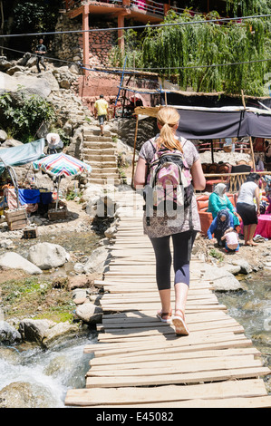 A female tourist crosses over a potentially dangerous rickety bridge over the Ourika River, Ourika Valley, Atlas Mountains, Morocco