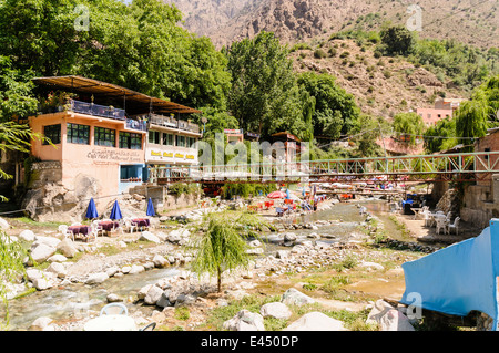 Plastic patio tables, chairs with parasols at restaurants on the banks of the Ourika River, Ourika Valley, Atlas Mountains, Morocco