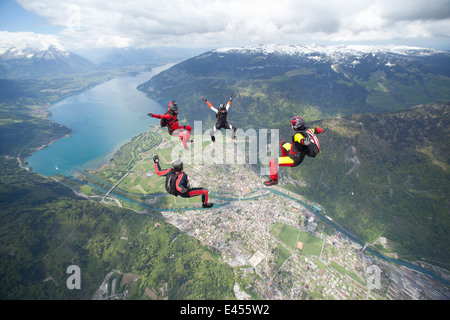 Team of four skydivers in formation over Interlaken, Berne, Switzerland Stock Photo