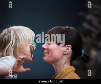Face to face portrait of mothers surprise at young sons painted face Stock Photo
