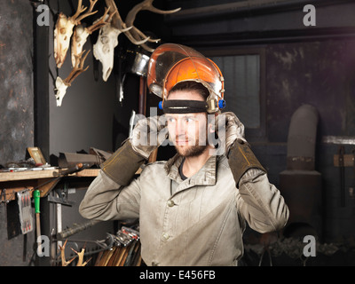 Blacksmith putting on a visor in workshop Stock Photo