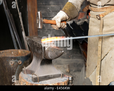 Cropped image of blacksmiths hammering a red hot metal rod Stock Photo