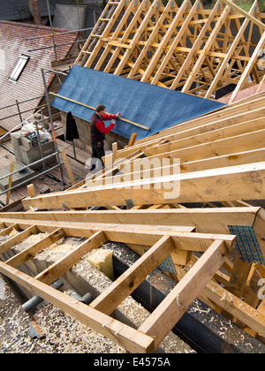 self building house, constructing roof, fixing laths onto traditional wooden trusses with breathable membrane Stock Photo