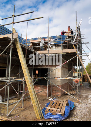 self building house, constructing roof, fixing laths onto traditional wooden trusses view from below scaffolding Stock Photo