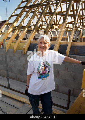 self building house, senior female self-builder on scaffolding at roof level Stock Photo