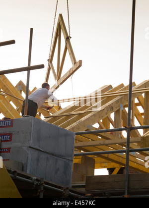self building house, constructing roof, lifting roof trusses into position with crane Stock Photo