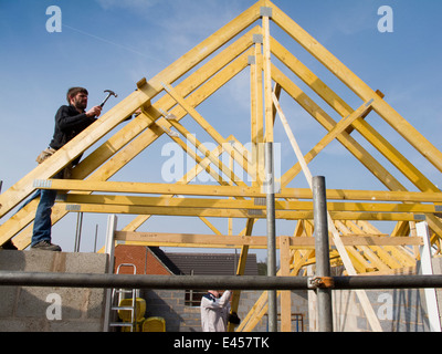 self building house, constructing roof, joiner fixing roof trusses in position Stock Photo