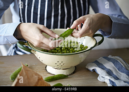 Man removing peas from pods