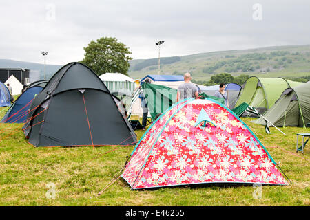 Pre-pitched tents in a field, rental camping accommodation in Kilnsey, Yorkshire Dales, July, 2014. Campers arrive and make preparations for the Tour de France. Thousands of cyclists have been in the Yorkshire Dales travelling the route of the Grand Depart. The fields assigned to parking and camping are now beginning to fill up in preparation for the cycling event on Saturday. Stock Photo