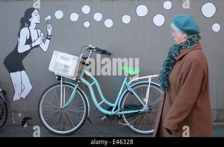city bike, or city bicycle with graffiti of a girl blowing bubbles on a wall in waterlooplein amsterdam, holland, netherlands Stock Photo