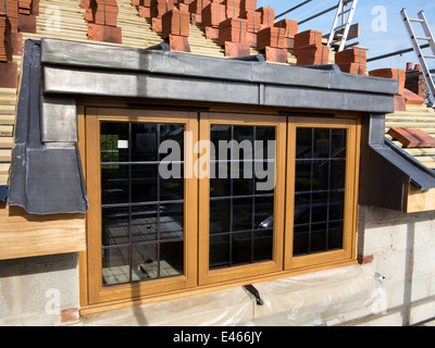 self building house, roof being tiled around traditional wooden dormer window Stock Photo