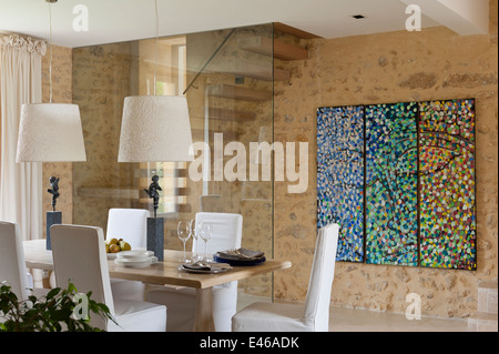 dining room with abstract painting on the wall, and dining table with two lampshades Stock Photo