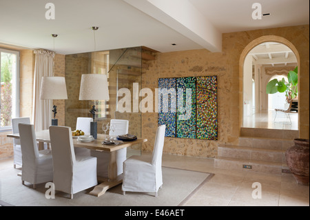 dining room with abstract painting on the wall, and dining table with two lampshades Stock Photo