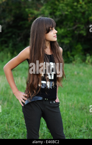 girl teen teenager transition age 13 14 15 years brunette hair long dark nature park open air beautiful portrait standing shirt Stock Photo