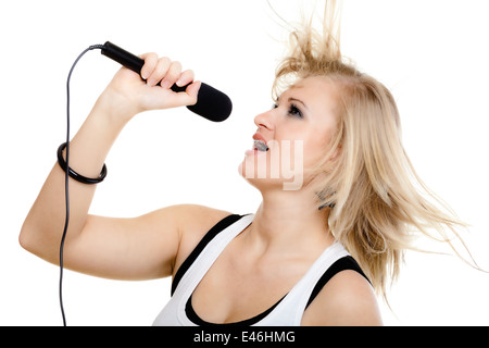 emotional blonde girl singer performer singing to microphone isolated on white. young pretty rockstar holding wireless mike Stock Photo