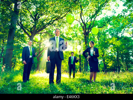 Group of business people holding balloons in the forest. Stock Photo