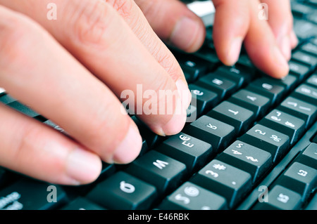 closeup of the hands of a man typing on a computer keyboard Stock Photo