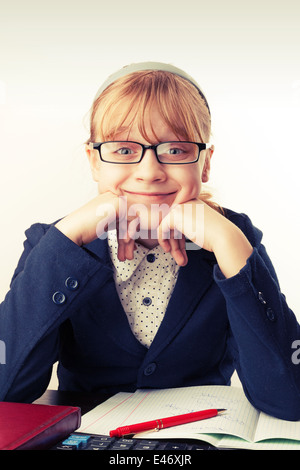 Little blond schoolgirl with glasses smiles above white. Toned effect Stock Photo