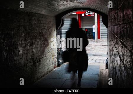 A woman walks through Pottenger's Entry, a pedestrian tunnel in Belfast city centre. Stock Photo