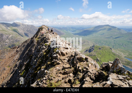 View back along red rocky Crib Goch ridge top scramble with hikers at start of Snowdon Horseshoe in mountains Snowdonia Wales UK Stock Photo