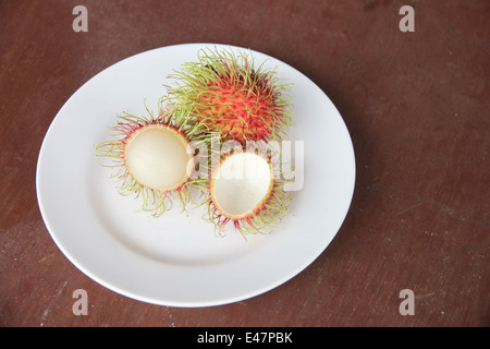 Fresh rambutan fruit of peeling in dish on the foods table. Stock Photo