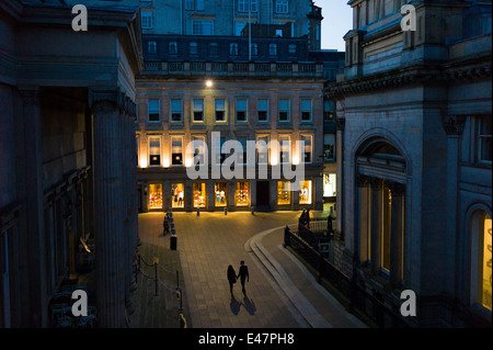 Couple holding hands and taking a nighttime stroll in Royal Exchange Square in the City Centre, Glasgow. SCOTLAND Stock Photo