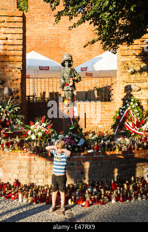 Child standing next to The Little Soldier monument to the Polish children who fought the Nazis during the Warsaw Uprising. Stock Photo