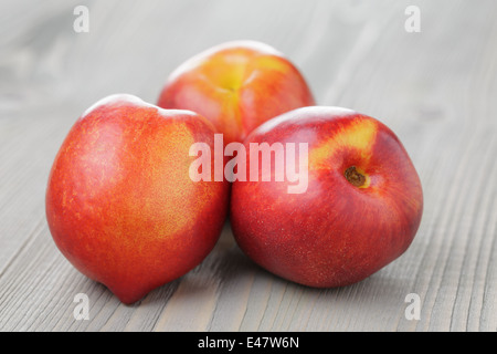 three ripe whole nectarines, on old wood table Stock Photo