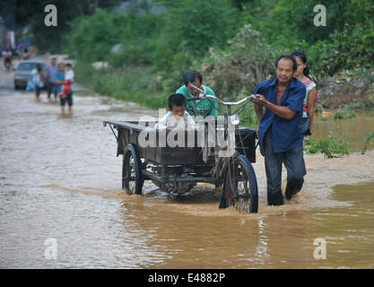 (140705) -- MASHAN, July 5, 2014 (Xinhua) -- A man pushes a tricycle in flood water in Mashan County, south China's Guangxi Zhuang Autonomous Region, July 5, 2014. Torrential rain hit Guangxi since July 4, where the precipitation exceeded 100 mm in 21 counties. (Xinhua/Zhang Ailin) (hdt) Stock Photo
