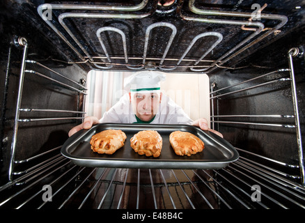 Chef prepares pastries in the oven, view from the inside of the oven. Cooking in the oven. Stock Photo