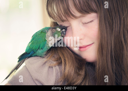 Portrait of girl (13-15) cuddling with parrot Stock Photo