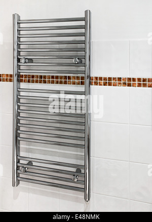 Chrome heated towel rail which serves a dual purpose as a radiator and towel dryer in modern bathrooms. Stock Photo