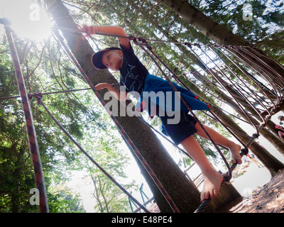 Boy balancing barefoot on rope in rope jungle gym Stock Photo