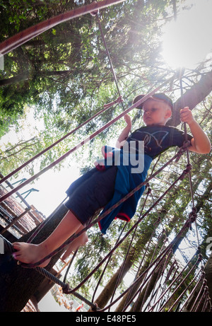 Boy balancing barefoot on rope in rope jungle gym Stock Photo