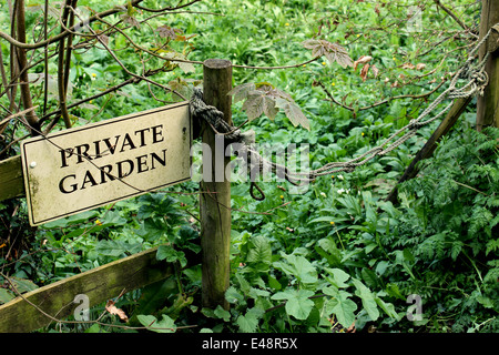 A private garden sign on a fence next to a rope gate to deter trespassers. Stock Photo