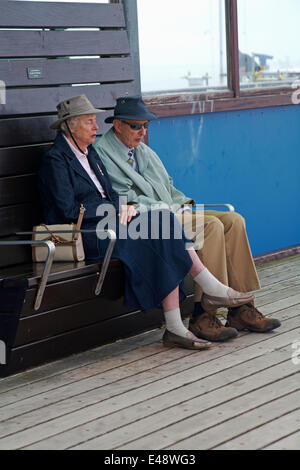 Bournemouth, UK. 6th July, 2014. Lack of sunshine doesn't stop visitors heading for the beach to catch the sun when it appears through the clouds and make the most of the weather on an overcast day. Old couple enjoying a snooze on the pier Credit:  Carolyn Jenkins/Alamy Live News Stock Photo