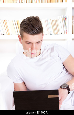 thoughtful young man chatting on laptop computer at home Stock Photo