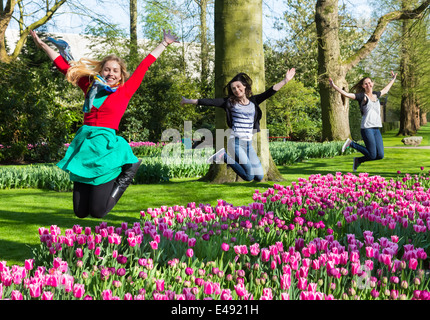 Three girls jumping above flowers field Stock Photo