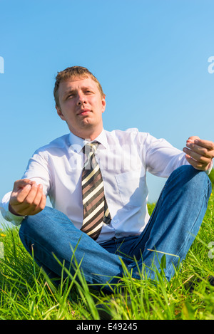 happy businessman relaxes in a field in the lotus position Stock Photo