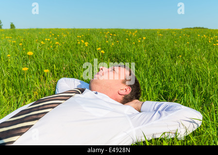 tired manager resting on green grass in field Stock Photo