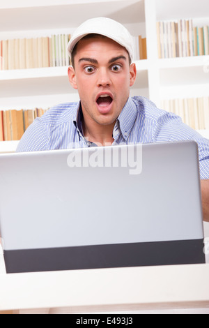 shocked business man wearing cap looking at his monitor with open mouth yelling having problem Stock Photo