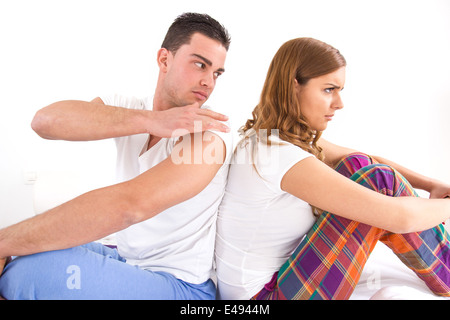 Portrait of an upset young couple sitting separately from each other on the bed in domestic bedroom atmosphere Stock Photo