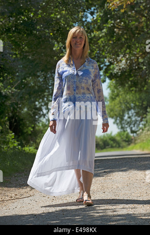 Woman walking in country Lane wearing blue and white outfit Stock Photo