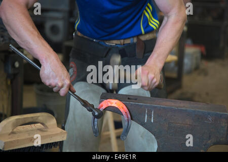 Calgary, Alberta, Canada. 06th July, 2014. Farrier holding hot horse shoe with fire tongs and shaping it with rounding hammer competes in the final round of the World Championships Blacksmiths' competition at the Calgary Stampede on Sunday, July 6, 2014. The top five farriers are competing for the title of world champion in this longstanding tradition at the Stampede. Calgary, Alberta, Canada. Credit:  Rosanne Tackaberry/Alamy Live News Stock Photo